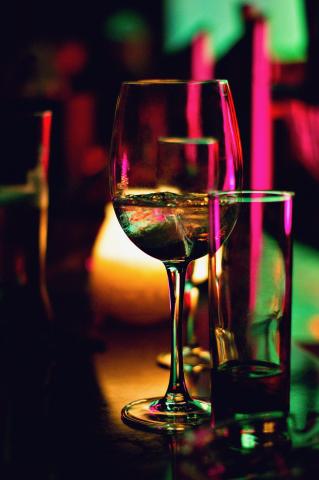 Wine glass and tall cocktail glass with green and purple lighting
